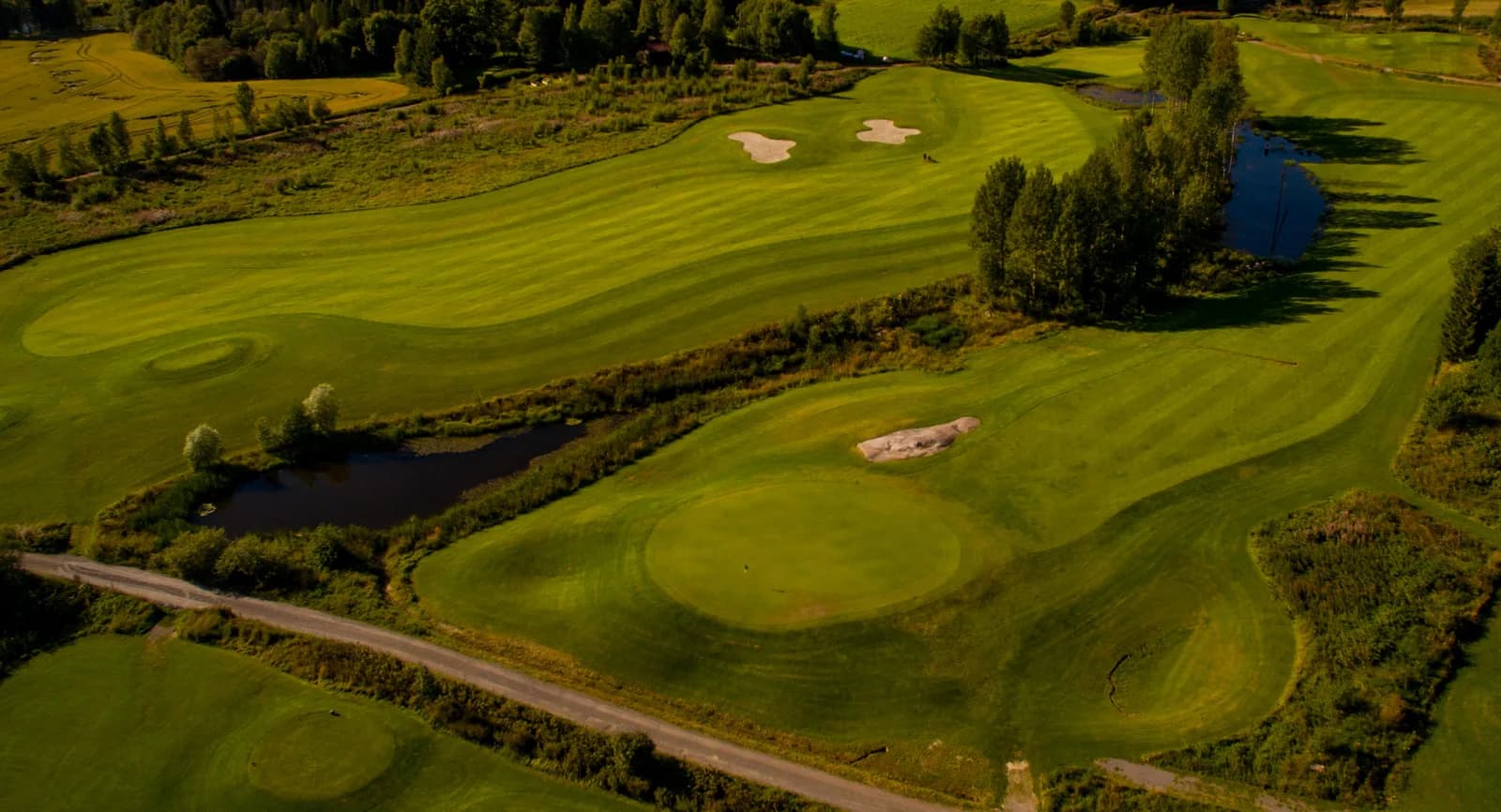 Aerial view of holes 15 and 16 at Aas Gaard Golf Park with water hazards and bunkers