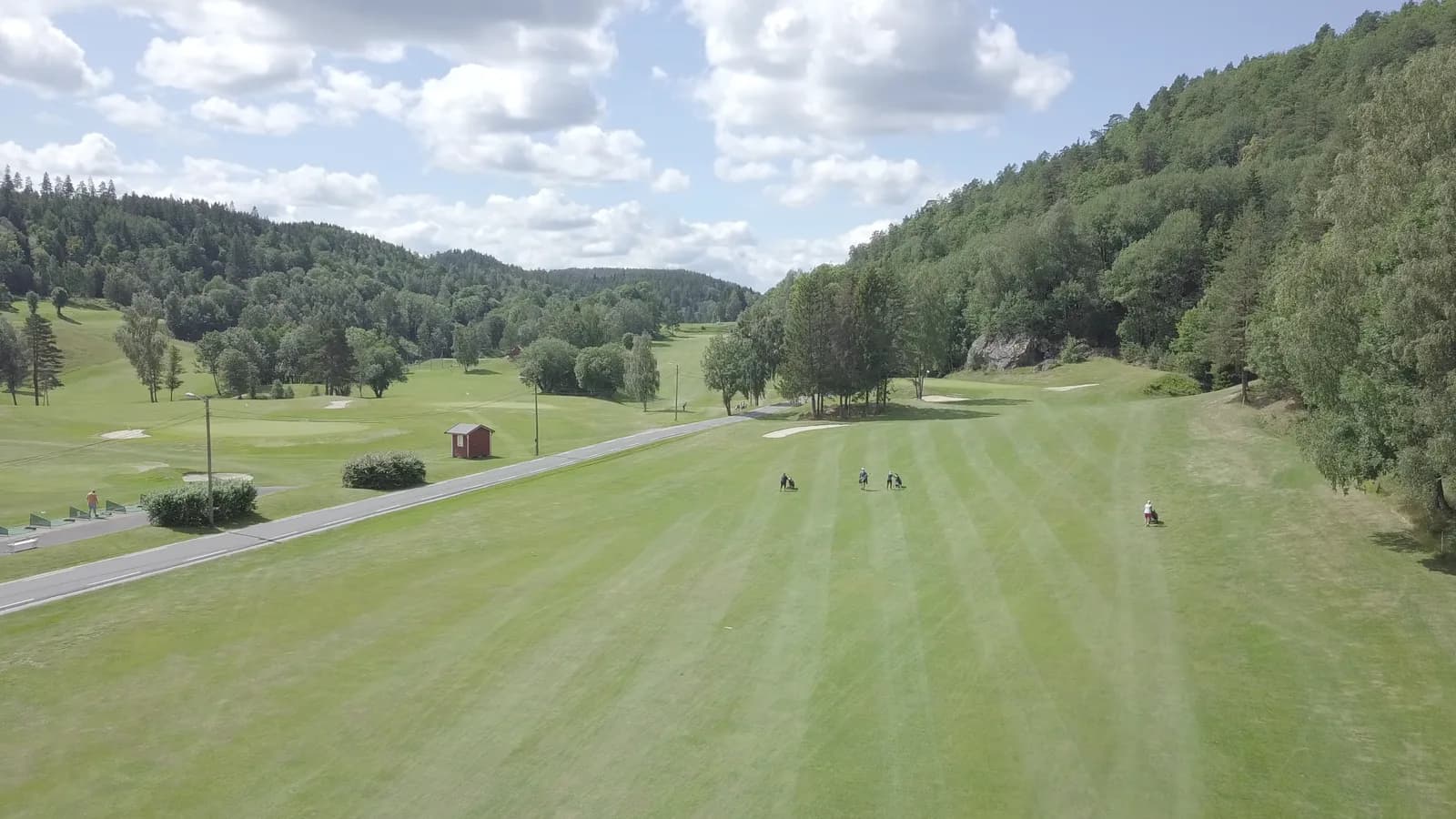 Wide fairway with golfers and green hills in the background at Arendal & Omegn Golf Club