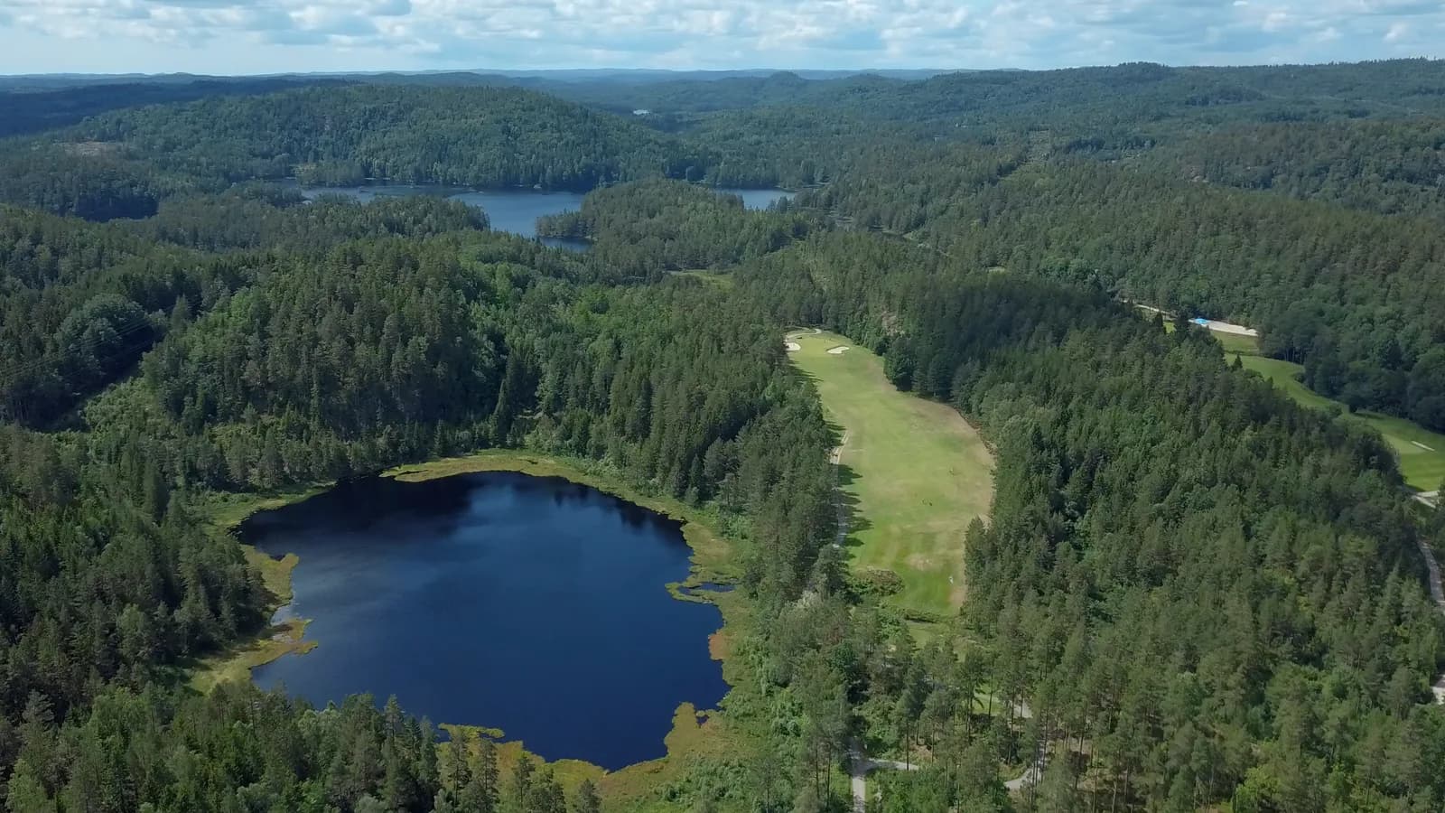 Aerial view of Arendal & Omegn Golf Club with lakes and forest from above