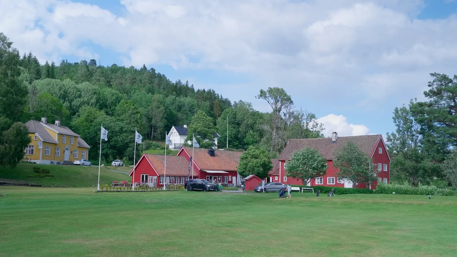 Clubhouse at Arendal & Omegn Golf Club with red and yellow wooden buildings at Nes Verk