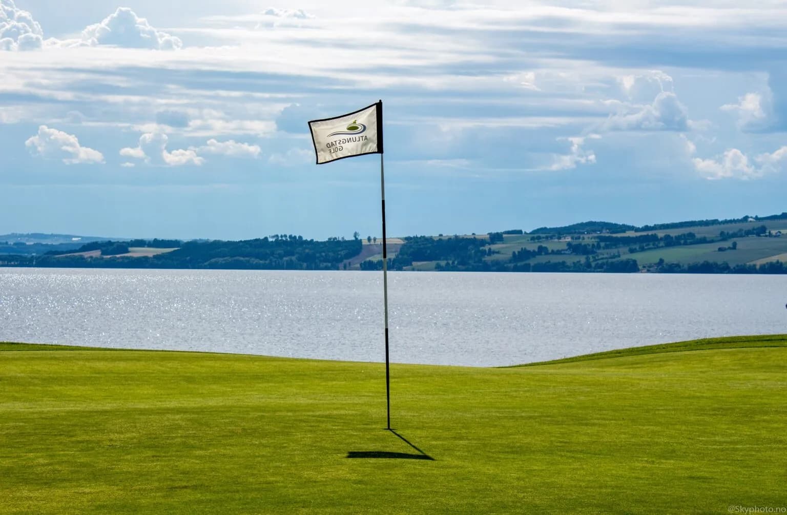 Golf green with flag and panoramic view over Lake Mjøsa at Atlungstad Golf Club