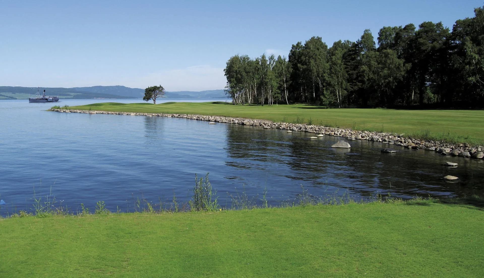 Green at Lake Mjøsa at Atlungstad Golf Club with water hazard and birch trees in Innlandet