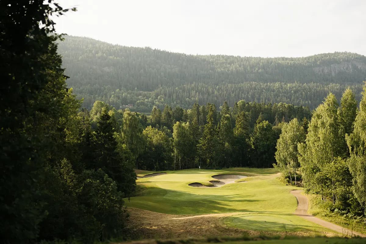 Green surrounded by bunkers and forest at Baerum Golf Club seen from elevated position