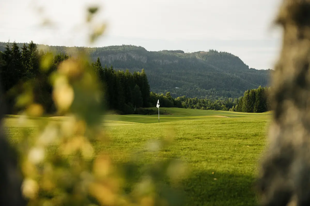 Green with flag pin at Baerum Golf Club with mountain views in the background