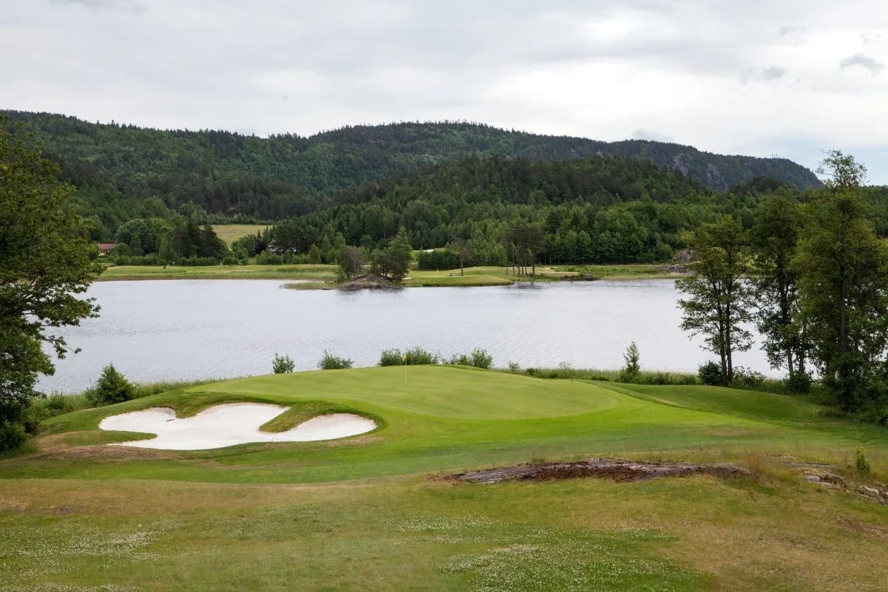 Green with bunkers at Bjaavann Golf Club overlooking Lake Bjåvann and forest landscape