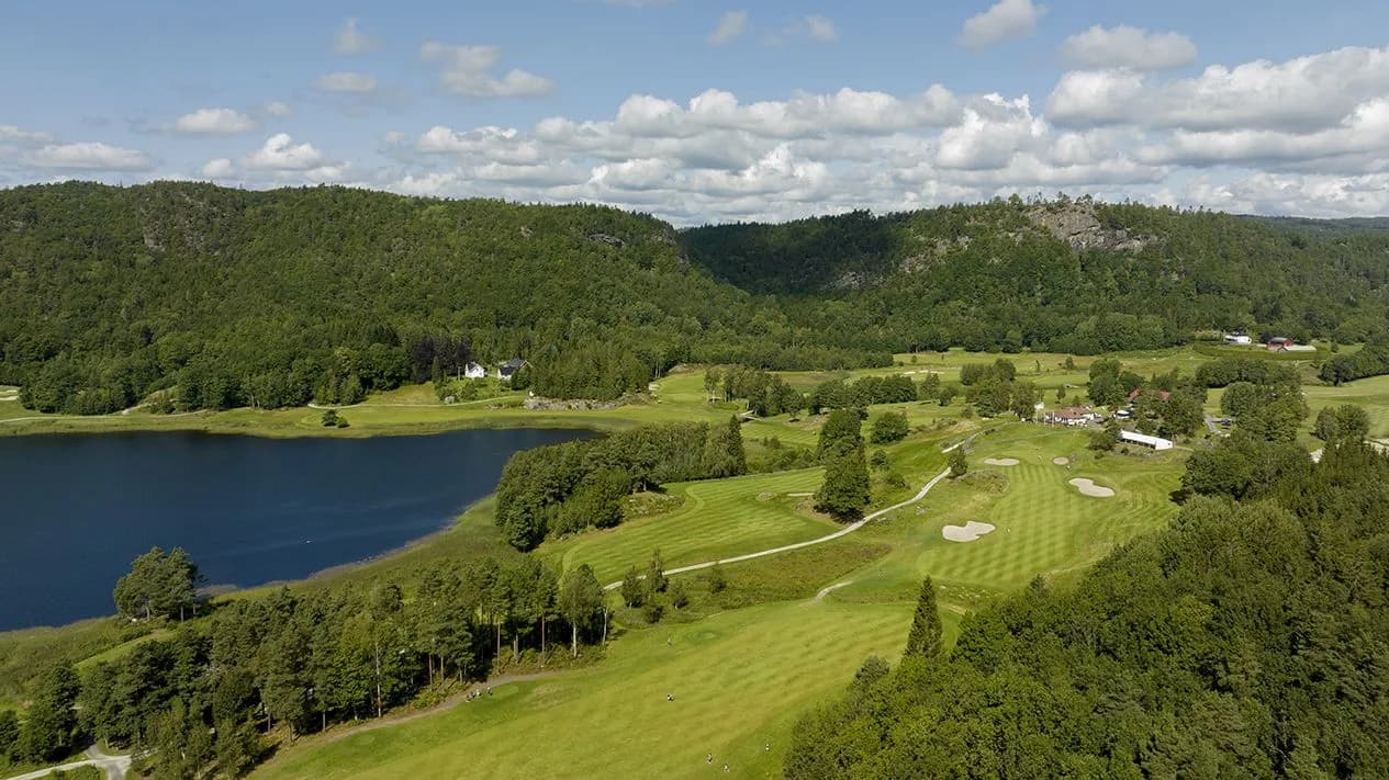 Overview of Bjaavann Golf Club with Lake Bjåvann, fairways and clubhouse in forest terrain by Ålefjær Fjord
