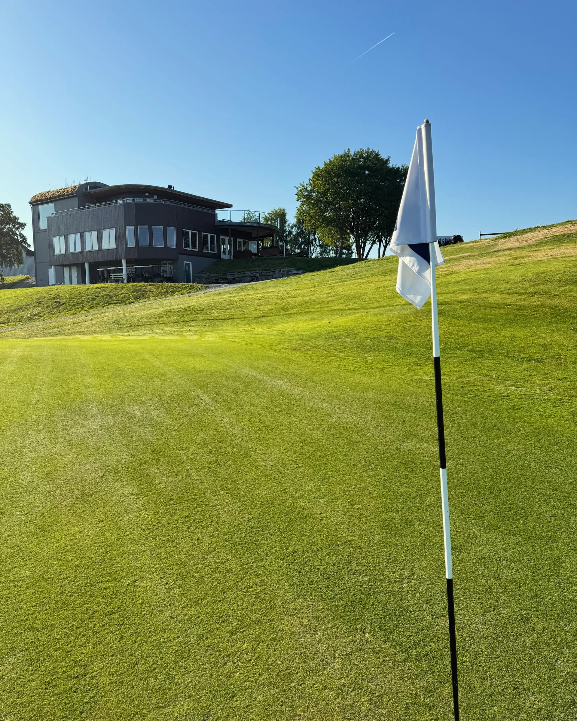 Green with flag and clubhouse at Byneset Golf Club in rural terrain near Trondheim