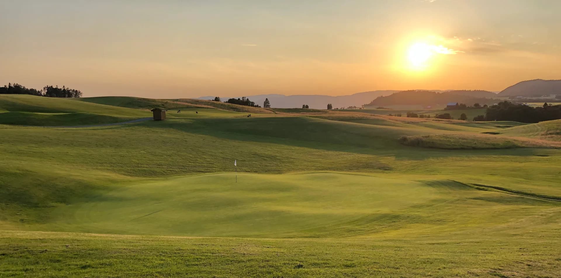 Sunset over Byneset Golf Club with players on the course in silhouette