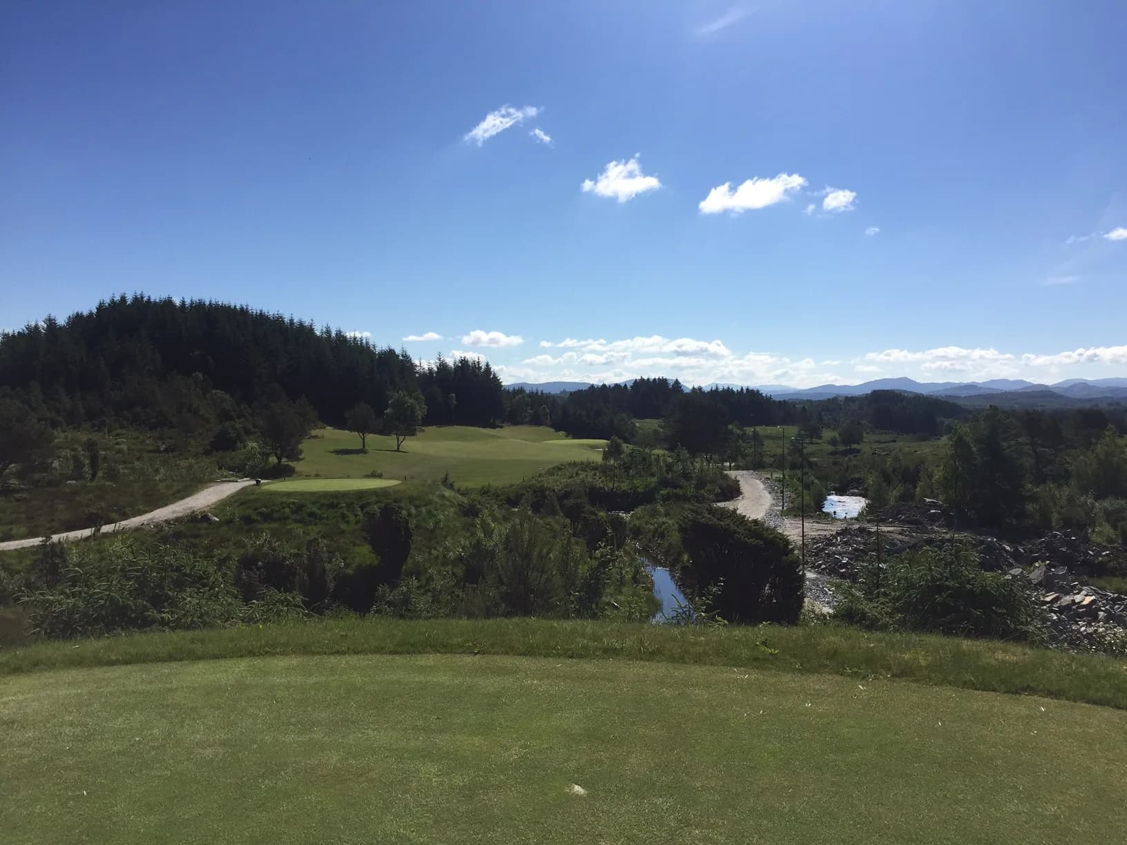 Panoramic view from hole 1 at Haugaland Golf Club with fairway, forest and mountains in the background