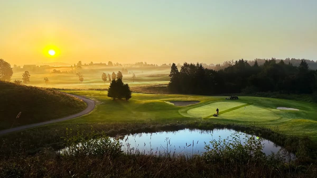 Sunrise over Hauger Golf Club with morning mist, green, water hazard and bunkers in golden light