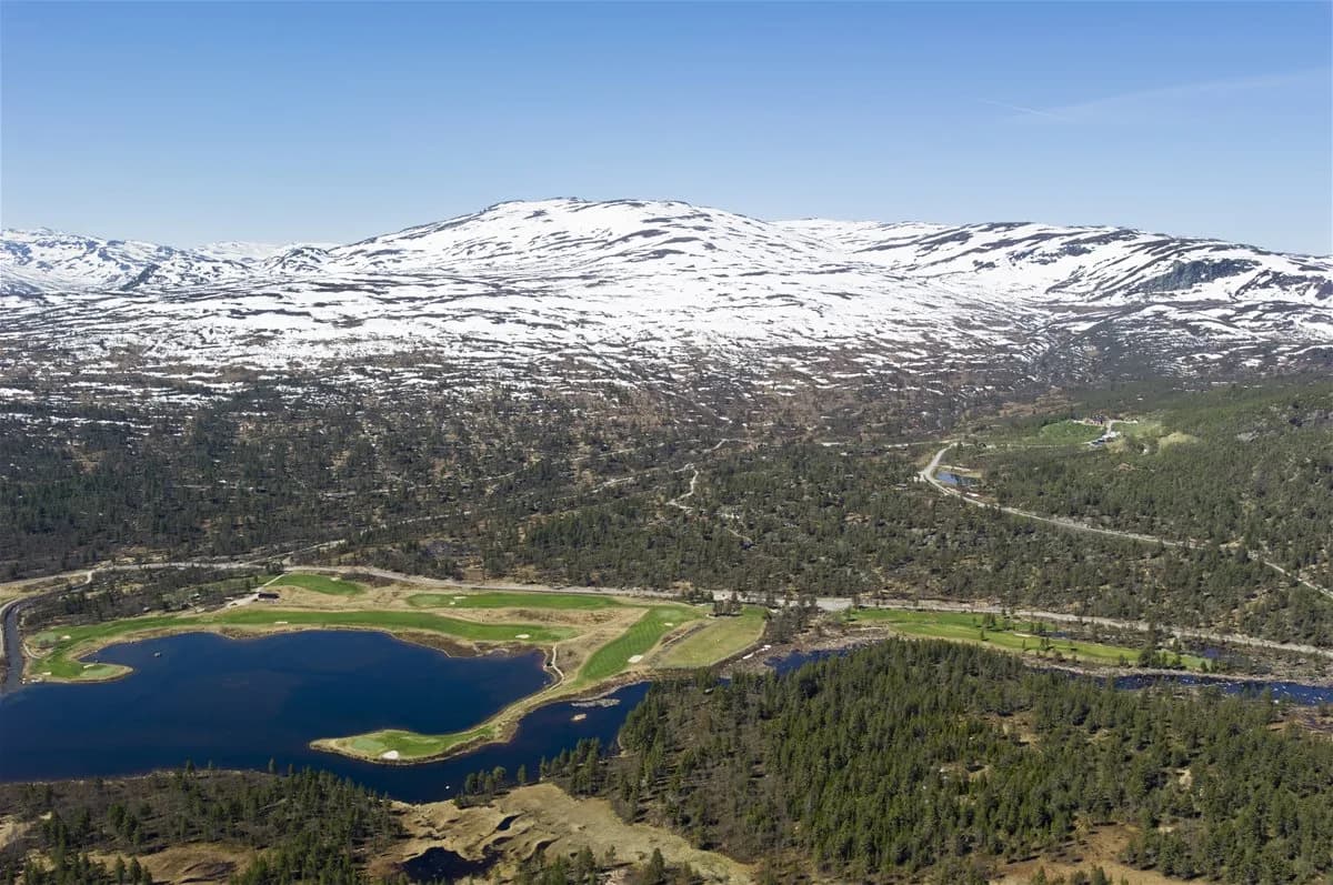 Aerial view of Hovden Golf Club highland course surrounded by lakes and snow-capped mountains in Setesdal
