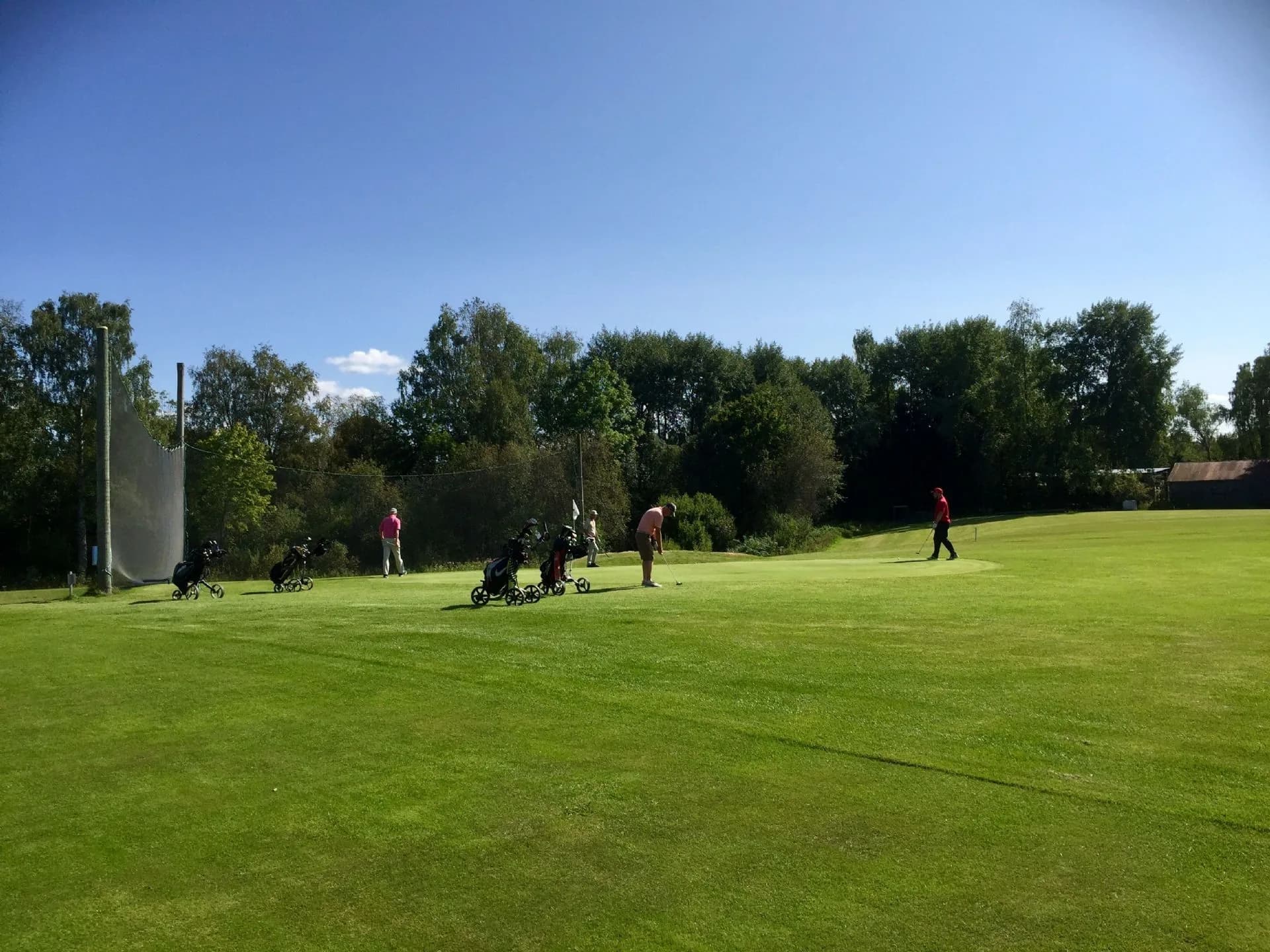 Fairway at Lillestrøm Golf Club with players on green surrounded by forest terrain