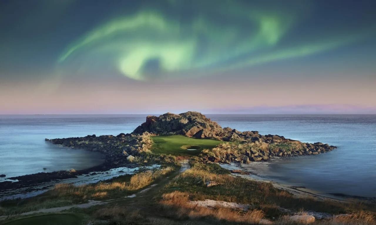 Oversiktsbilde av Lofoten Links golfbane langs kystlinjen med fjell i bakgrunnen