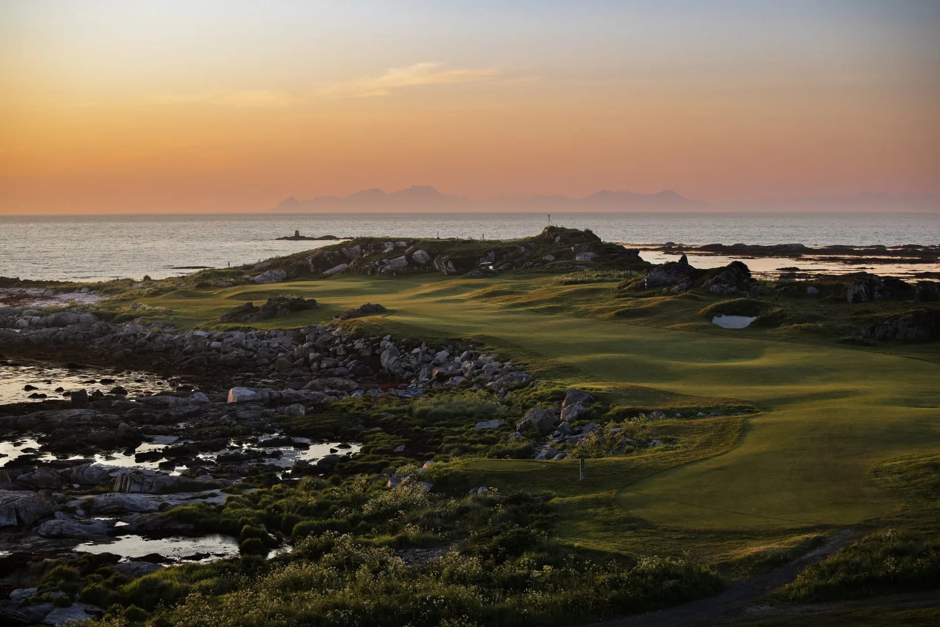 Flyfoto av Lofoten Links golfbane ved kysten med fjell og nordlys i Lofoten