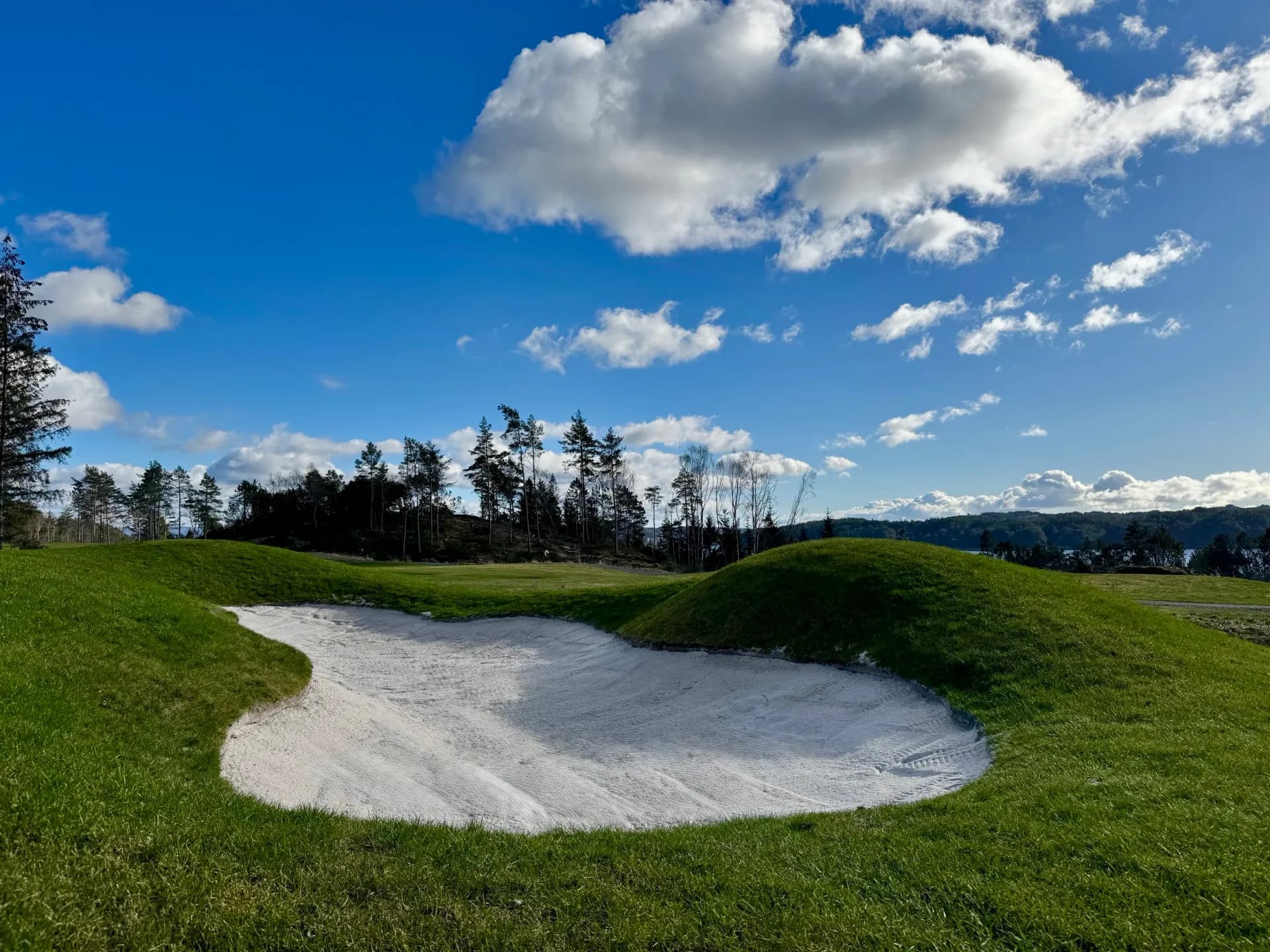 Golf course at Meland Golf Club with bunkers, green fairways and mountains in the background