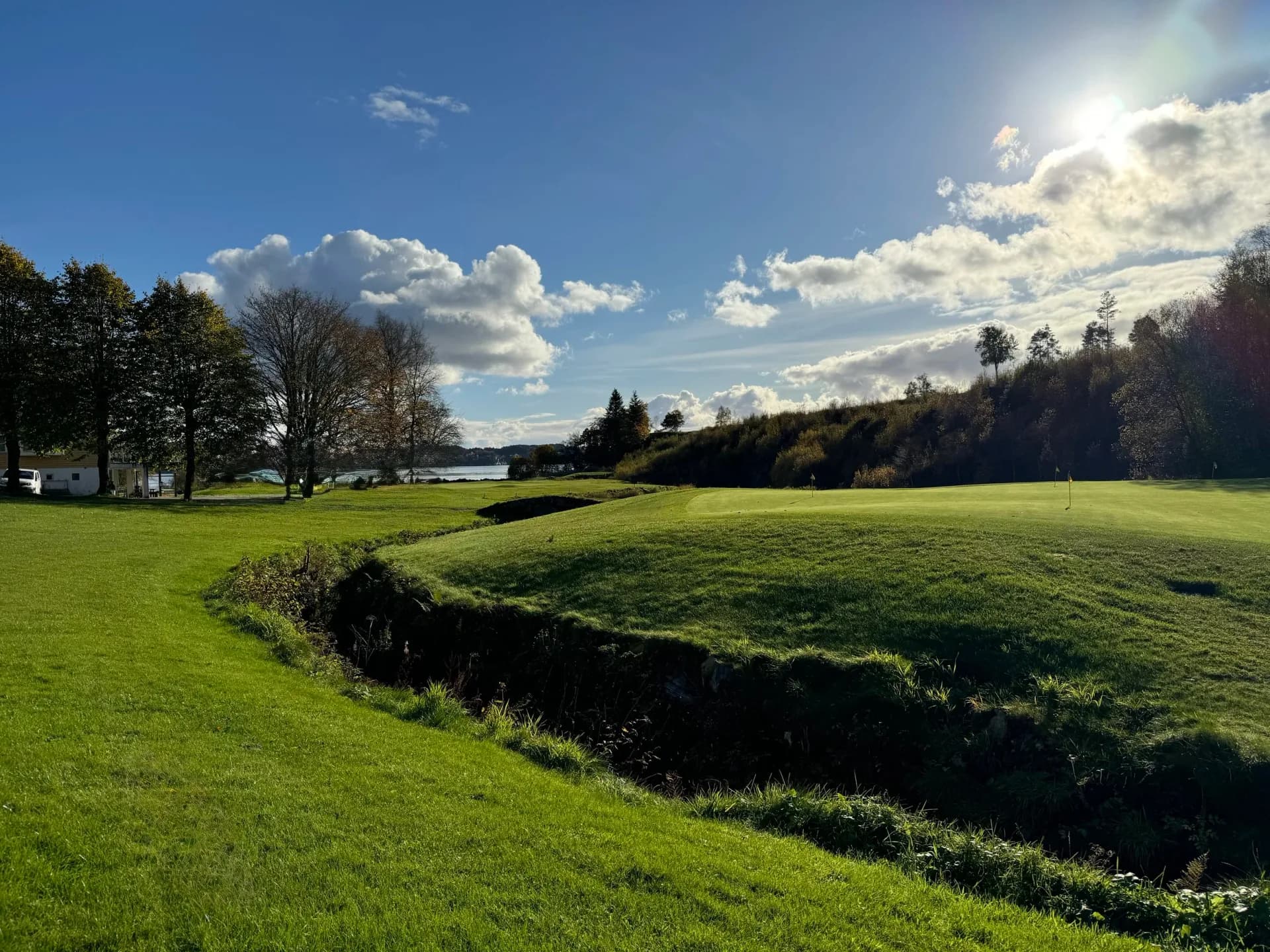 Fairway at Meland Golf Club with water hazard and mountain landscape in the background under blue sky