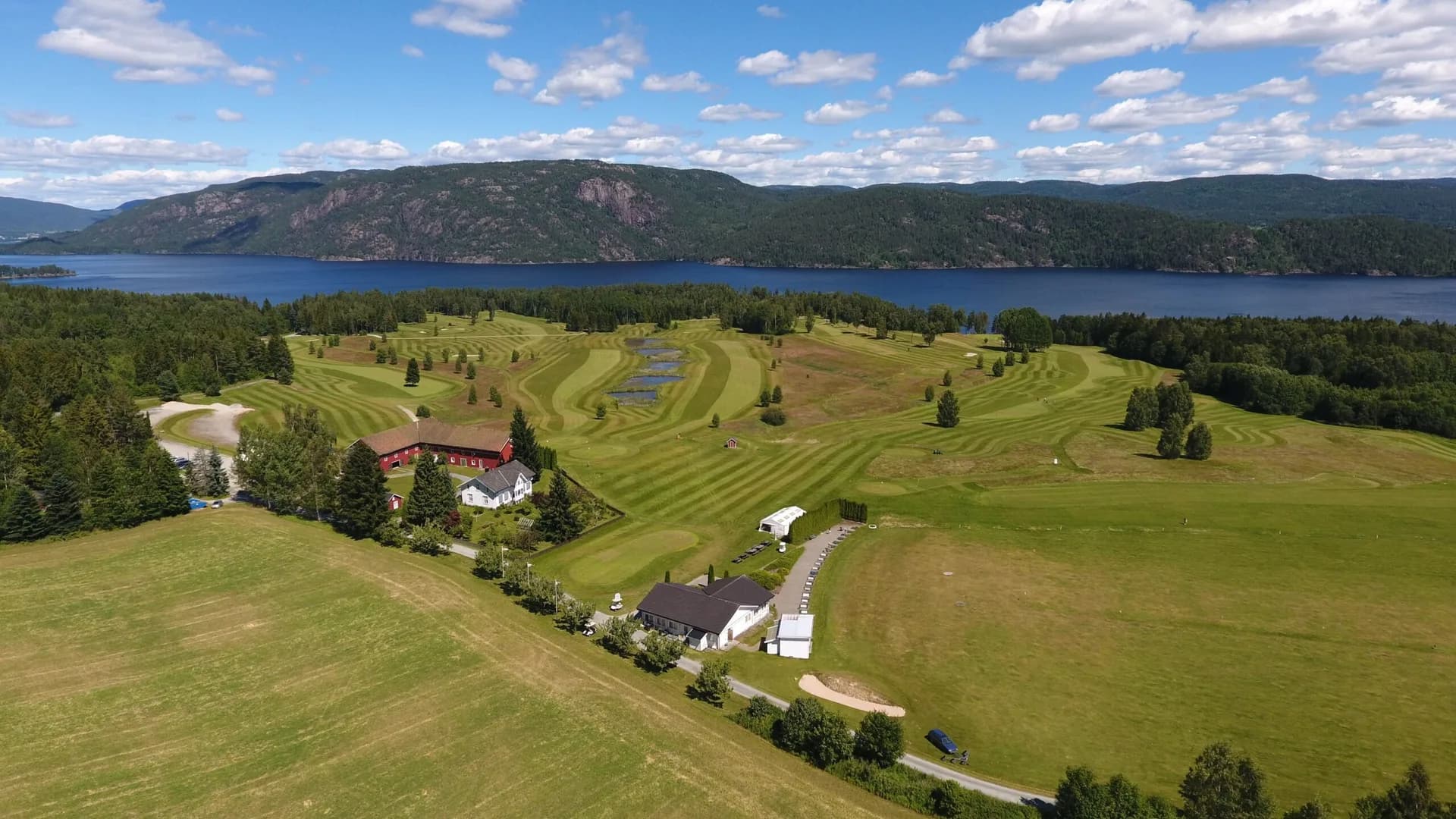 Aerial view of Norsjø Golf Club with clubhouse and golf course surrounded by green forests in Telemark