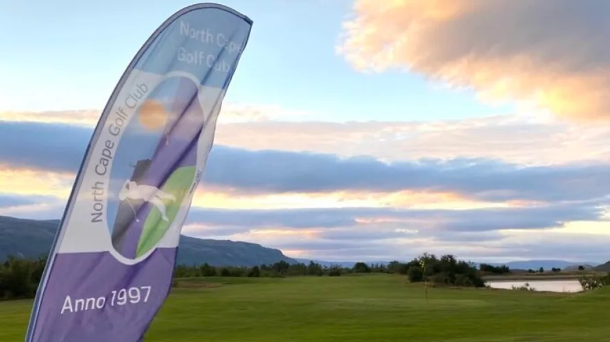 Banner med North Cape Golf Club Anno 1997-logo foran linksbanen under midnattssolen
