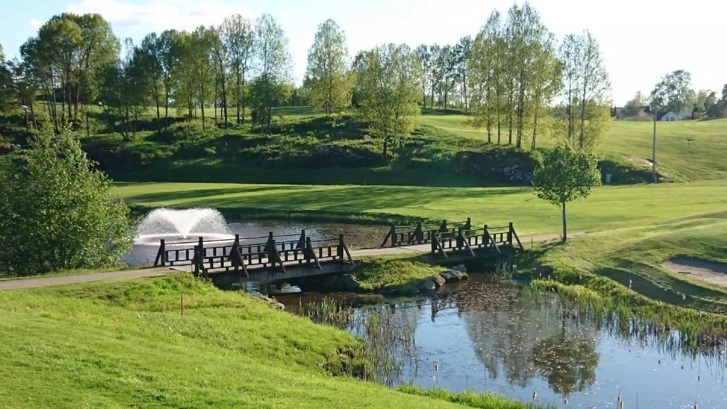 Oppegård Golf Club with water hazard, wooden footbridge and rolling course in scenic forest terrain