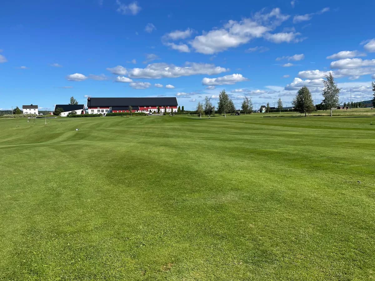 Fairway on hole 1 at Romerike Golf Club with clubhouse and blue sky in Aurskog