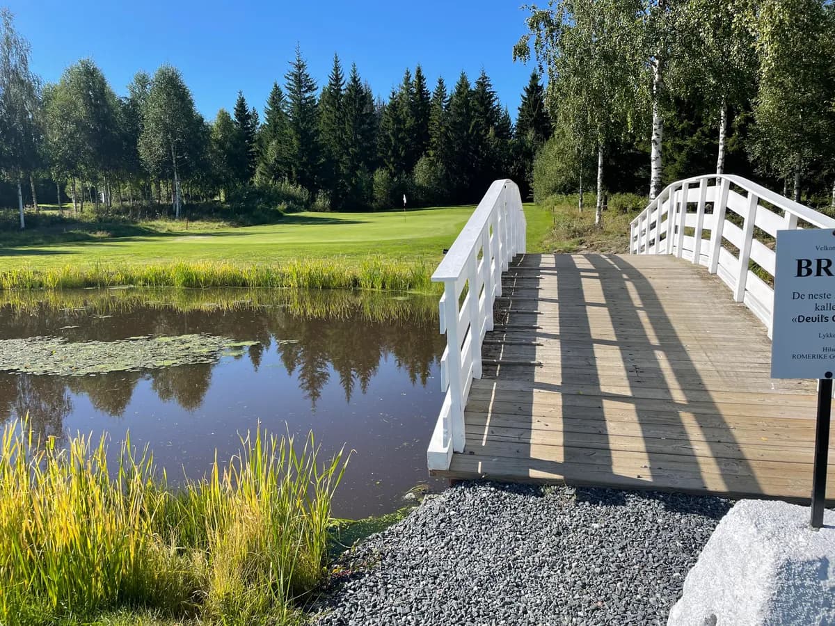 White bridge over water hazard at hole 12 at Romerike Golf Club with birch trees and green fairway