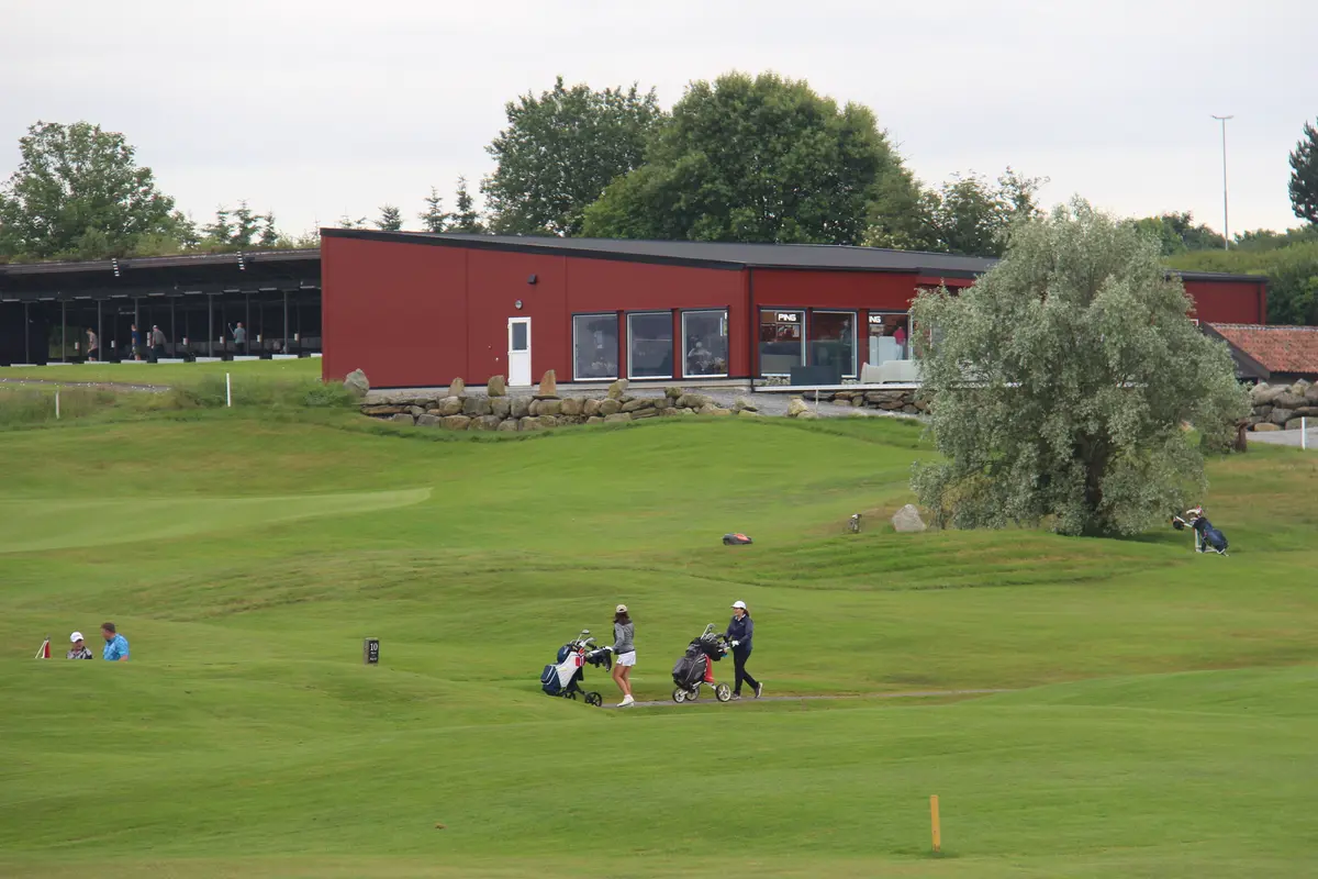 Golfers at Sandnes Golf Club with the clubhouse and driving range in the background