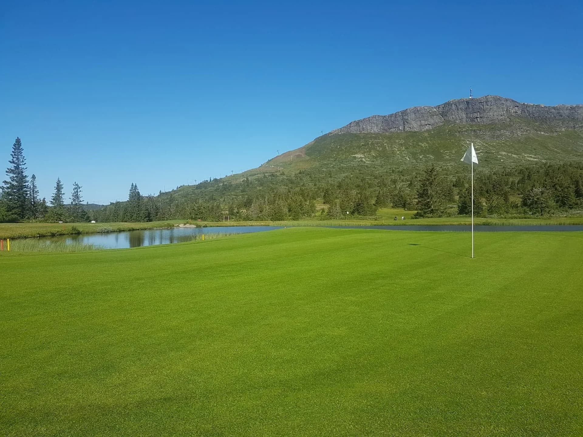 Hole 6 at Skei Golf Club with close-up of green and Skeikampen mountain in the background
